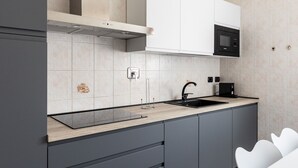Una cocina moderna con armarios grises, un lavamanos negro y un microondas.