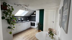 Une cuisine moderne avec des armoires blanches, un four encastré et une lucarne.