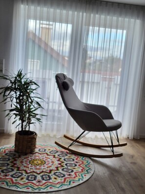 Una habitación moderna con una mecedora, una planta en maceta y una alfombra colorida.