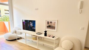 A modern living room with a flat-screen TV, a white console table, and two round armchairs. - Pink Alta Apartment With Pool (Puerto de la Cruz)