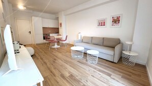 A modern living room with a sofa, coffee table, and chairs, a kitchen in the background, and a dining area with a table and chairs. - Pink Alta Apartment With Pool (Puerto de la Cruz)