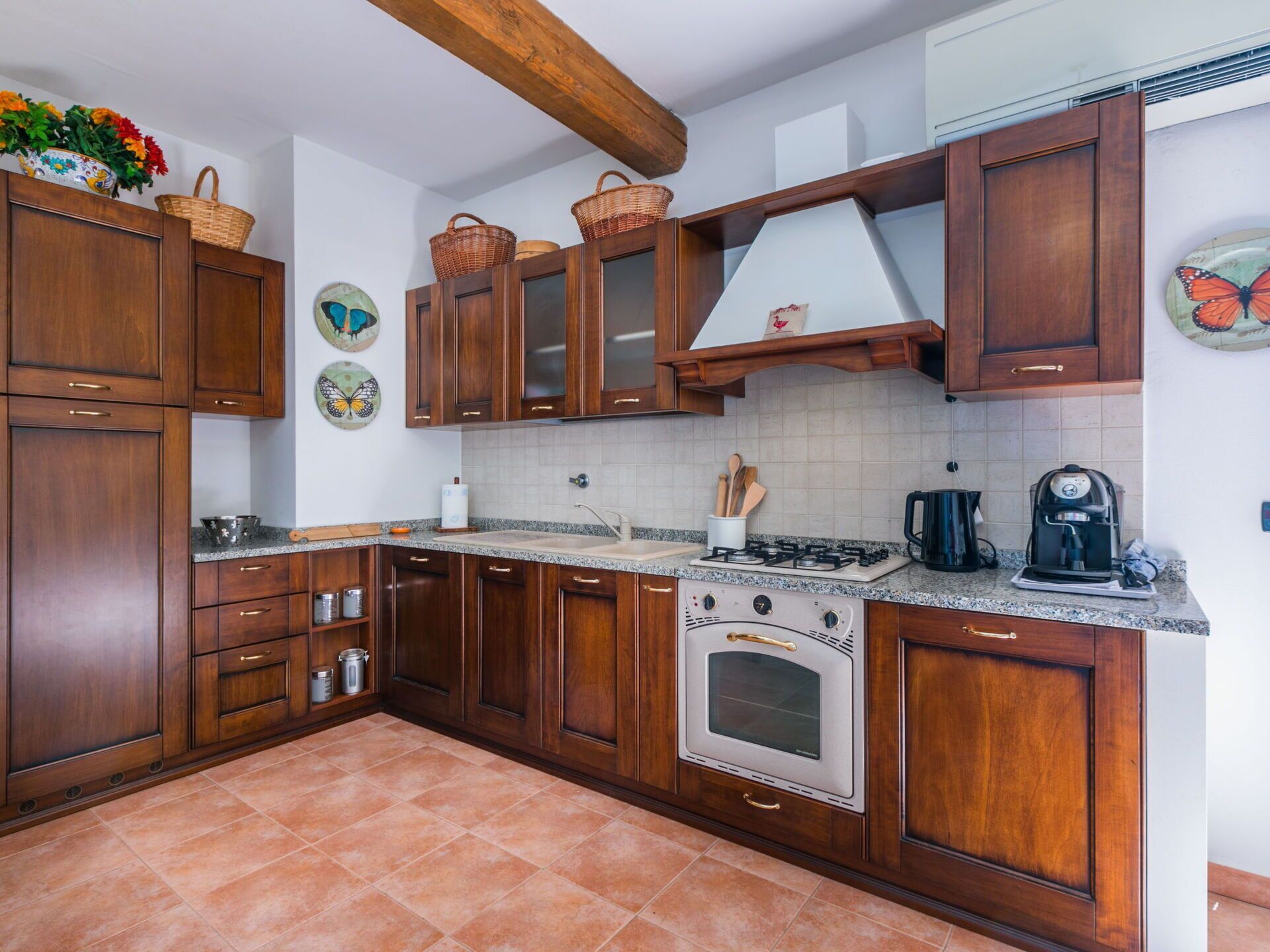 A kitchen with wooden cabinets, a gas stove, an oven, and a coffee maker.