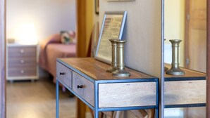 Ein Schlafzimmer mit einem Holzschrank, einem Nachttisch mit Lampe und einem gerahmten Bild an der Wand.