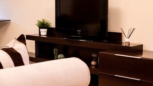 A modern hotel room with a flat-screen TV on a wooden stand, a small potted plant, and a decorative hourglass. - Céntrico Apartamento en Santa Cruz (Santa Cruz de Tenerife)
