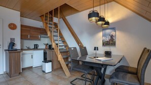 A modern kitchen with wooden cabinets, a built-in stove, and a coffee machine.