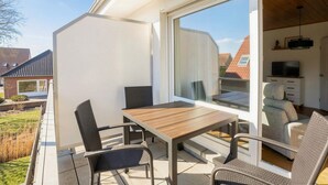 A patio with a table and chairs, a sliding glass door, and a TV in the background.