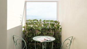 Un petit balcon avec une table et des chaises, entouré d’un mur végétal.