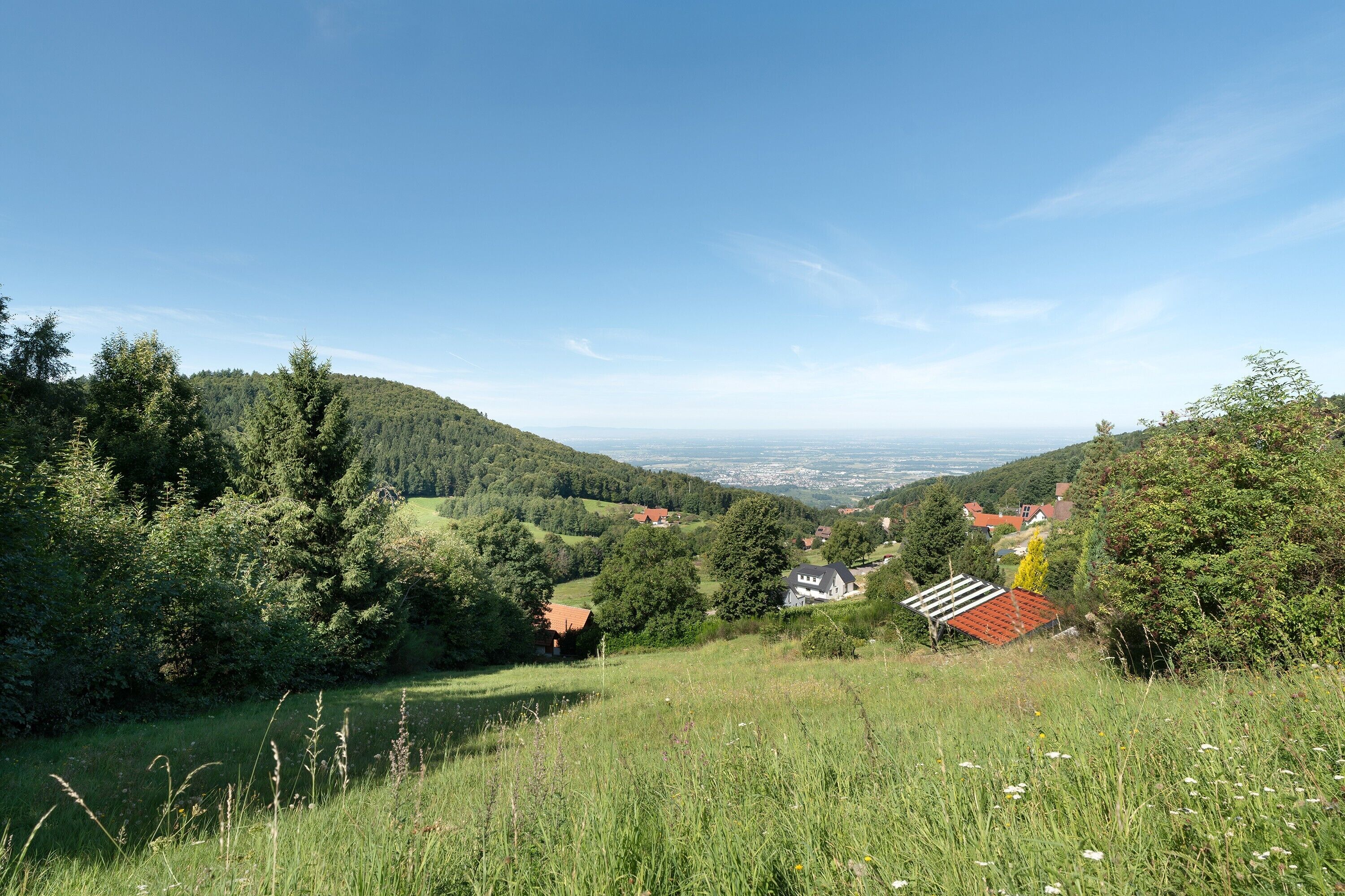 A rural landscape with rolling hills, a clear sky, and scattered houses.