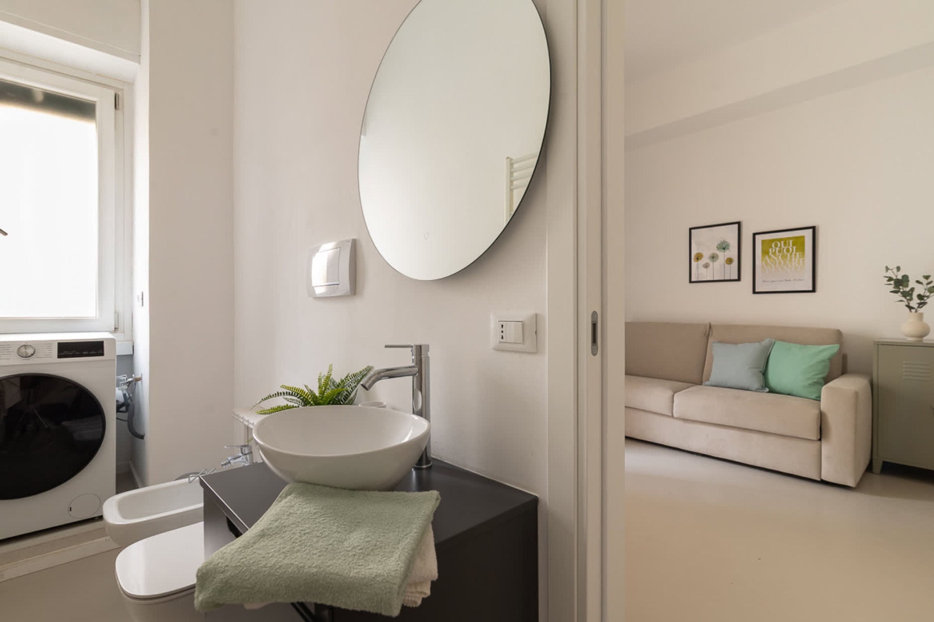 A modern bathroom with a sink, mirror, and a washing machine.