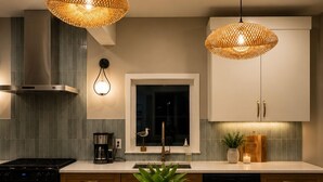 Une cuisine moderne dotée d’un îlot central, de luminaires suspendus et de tabourets de bar.