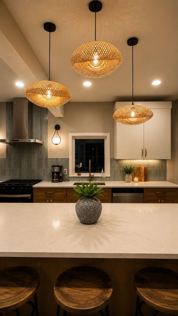 A modern kitchen with a central island, pendant lights, and bar stools.