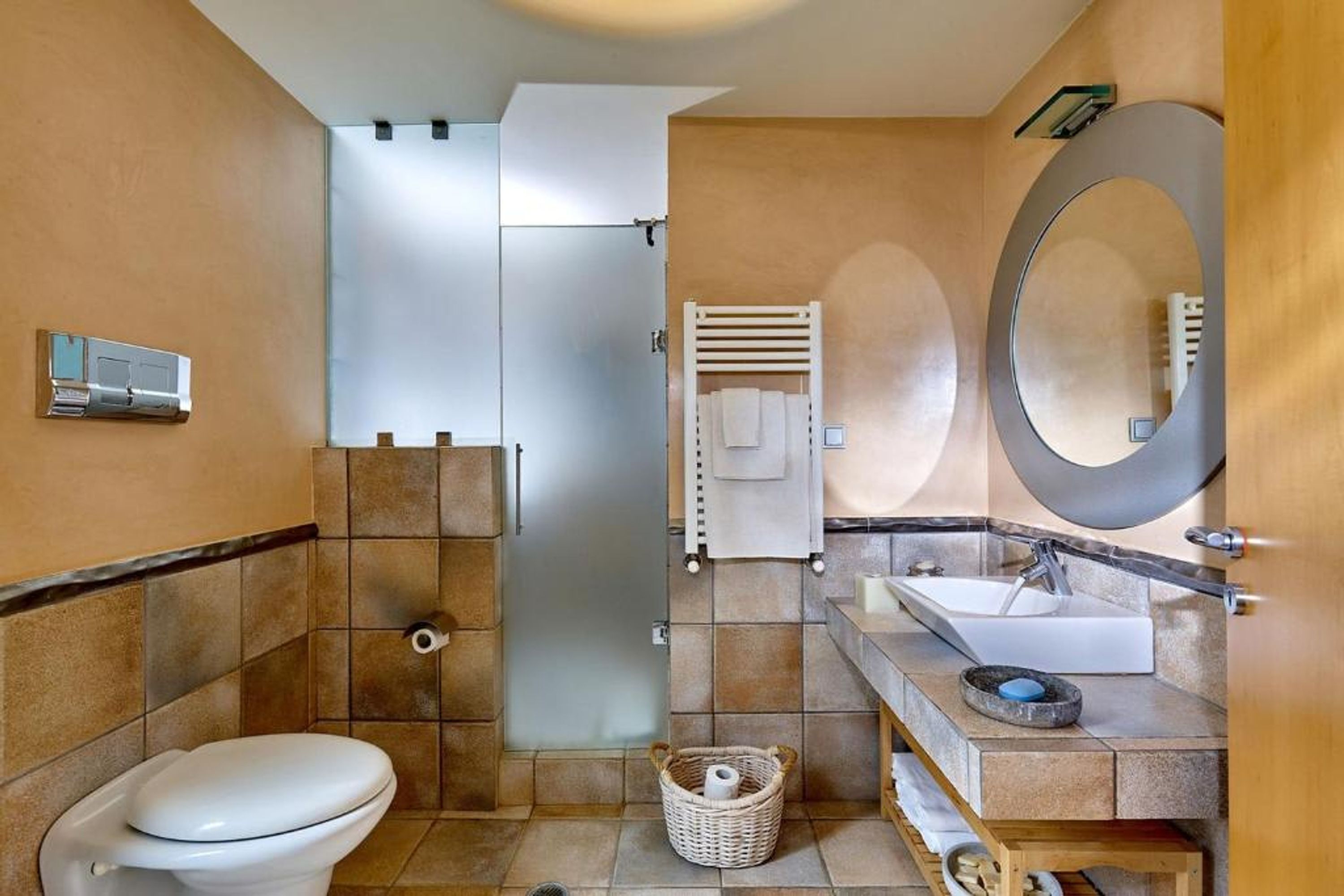Een moderne badkamer met toilet, douche en wastafel.