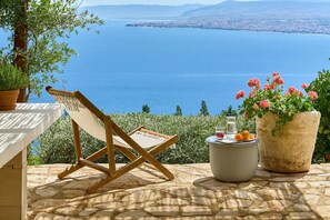 A stone terrace with a wooden chair and a potted plant, overlooking a coastal view. - Villa Vollard Panoramic Seaview Private Pool (Malevizi)