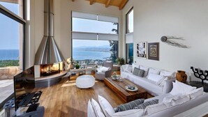 A modern living room with a fireplace, white furniture, and large windows overlooking a scenic view. - Villa Vollard Panoramic Seaview Private Pool (Malevizi)