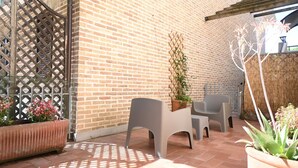 Un patio con paredes de ladrillo, cerramiento de celosía y plantas en macetas.