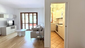 Un apartamento moderno con sala de estar, una mesa de comedor, sofá y cocina visible a través de una puerta abierta.