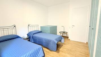 Una habitación con dos camas, una mesita redonda y una puerta.