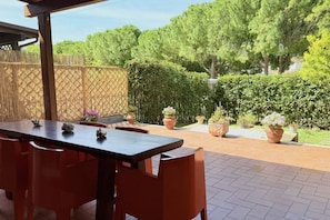 An outdoor patio with a wooden table and chairs, surrounded by potted plants and a wooden fence. - Location: quiet and central area of ​​Sirolo, 150 meters from the square and the path that leads to the beach, reachable on foot.Description: apartment located on the ground floor with garden. Living room with sofa and dining table - separate kitchen (Sirolo)