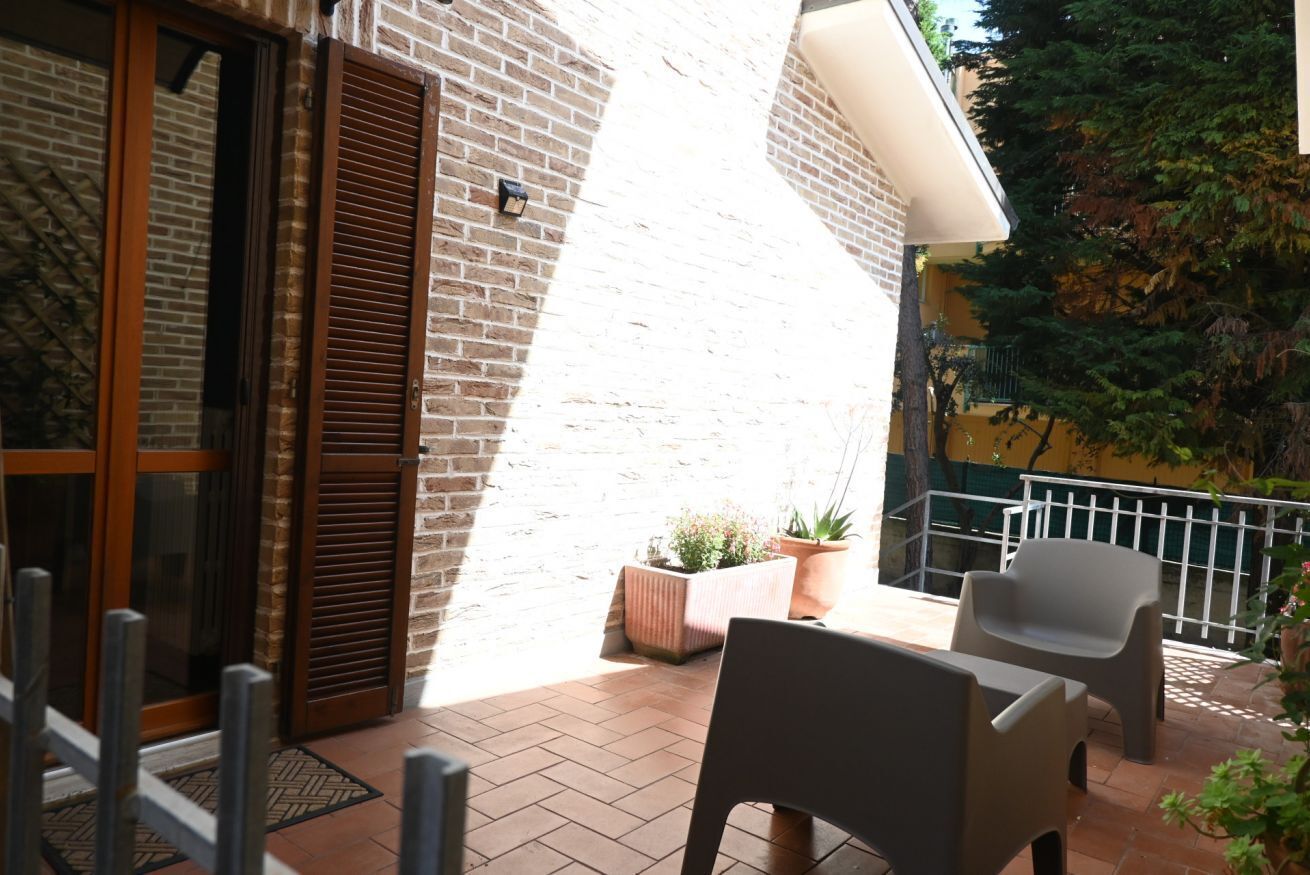 Un patio con pared de ladrillo, puerta corrediza de vidrio y dos sillas.
