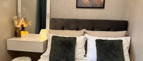 A hotel room with a bed, a nightstand, a mirror, and a wall-mounted picture.