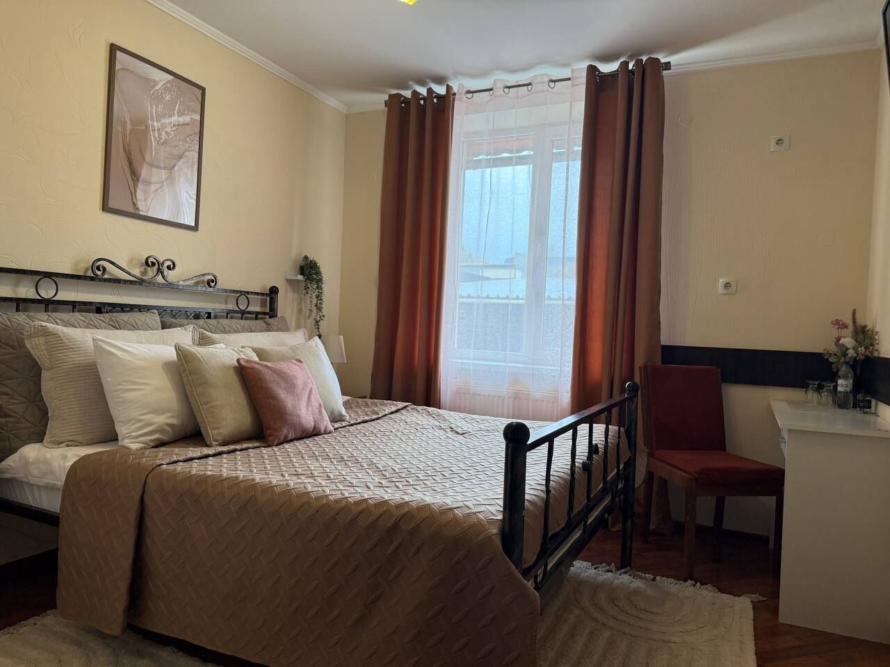 Une chambre à coucher avec un lit, une chaise, un bureau et une fenêtre avec des rideaux.
