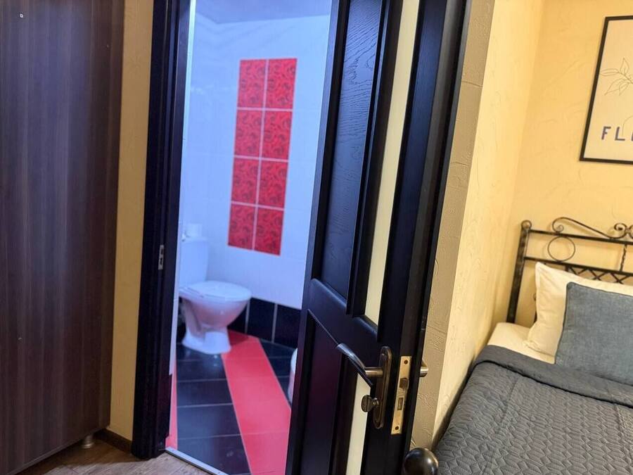 Una habitación de hotel con una cama, una puerta que da a un baño y un suelo rojo y negro.
