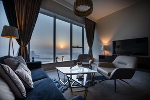 A modern living room with a sofa, a coffee table, and a TV. - Maison Privee - Chic Coastal Escape w/ Sea Views on Palm Entry (Dubai)