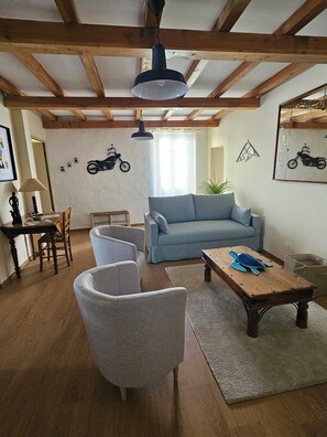 Un salon avec un canapé, des fauteuils, une table basse et une lampe suspendue.