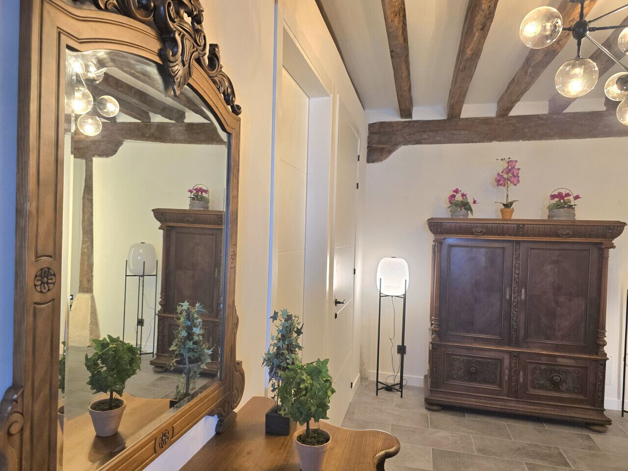 A room with a large ornate mirror, a wooden cabinet, and a floor lamp.