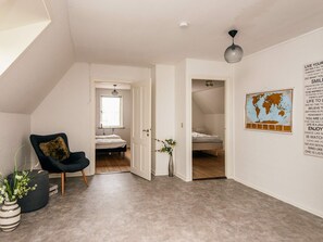 Una stanza con un letto, una sedia, una mappa appesa al muro e una lampada a soffitto.