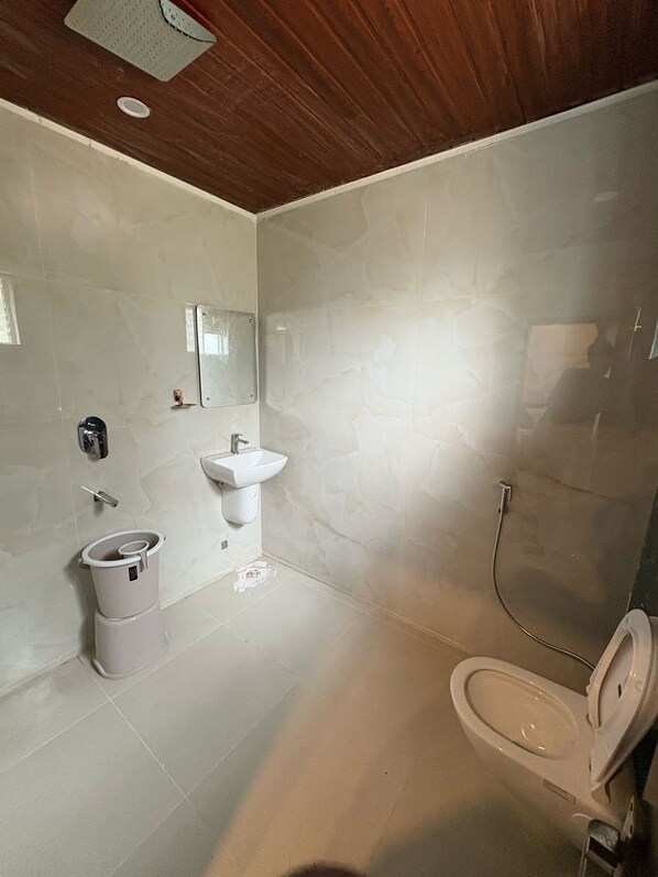 A modern bathroom with a toilet, sink, and shower. - 5th Avenue (Visakhapatnam)