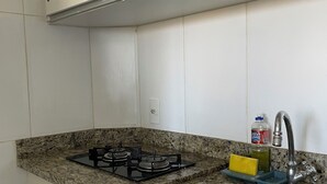 A kitchen with white cabinets, a granite countertop, a gas stove, a sink, and a soap dispenser. - 1 bedroom apartment in Lagoa Quente flat service (Caldas novas)