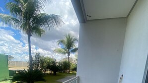 A balcony with a view of palm trees and a grassy area. - 1 bedroom apartment in Lagoa Quente flat service (Caldas novas)