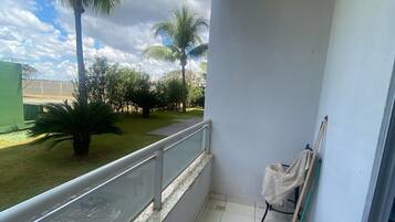 Varanda com vista para palmeiras e um gramado.