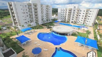 Um hotel com vários edifícios, uma piscina central e áreas de estar ao ar livre.
