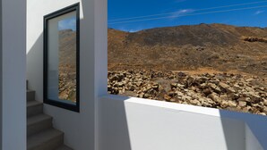Eine Treppe führt zu einem Balkon mit Blick auf felsiges Gelände und einen klaren Himmel.