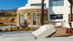 Uma villa moderna com fachada de pedra, janelas amplas e área de piscina com espreguiçadeiras.