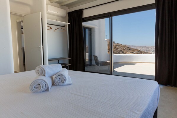 A hotel room with a large bed, a wardrobe, and a balcony with a view. - HoM Mykonos Sea View Villa With Private Pool (Mykonos)