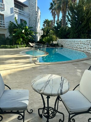 Een buitenzwembad, parasols bij het zwembad en ligstoelen