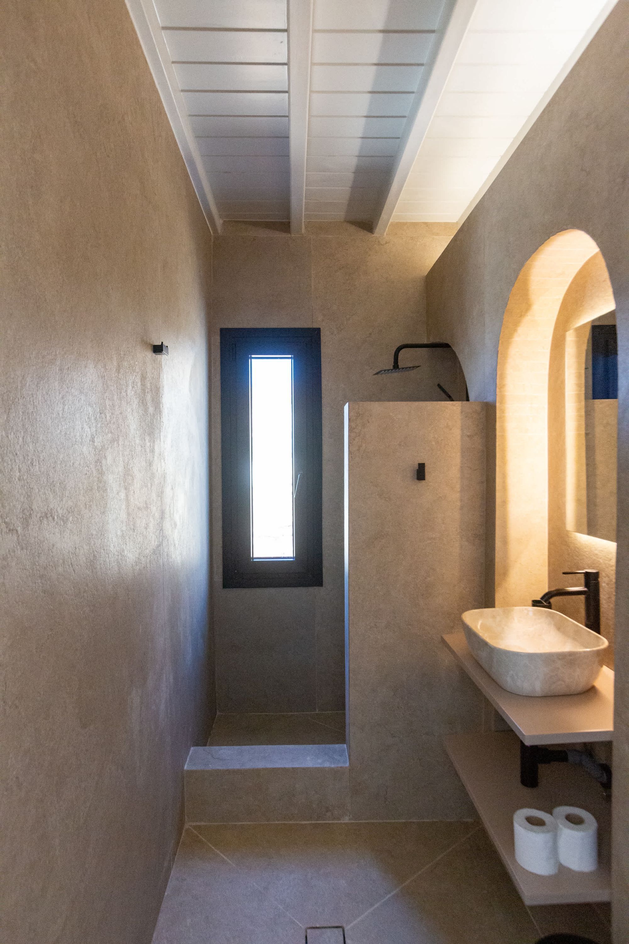 A modern bathroom with a large window, a freestanding sink, and a shower area.