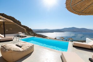 A pool area with lounge chairs and a view of the sea. - Apellon Mykonos Luxury Seaview Retreat (Mykonos)