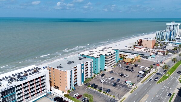 Um hotel à beira-mar com vários andares, estacionamento e vista para a praia e oceano.