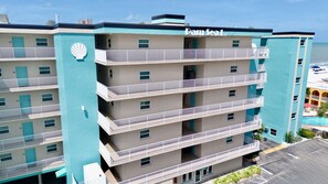 Um hotel com vários andares, varandas, área de piscina e vista para o mar.