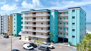 Um hotel com vários andares, varandas, estacionamento e vista para o oceano.