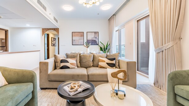 A modern living room with a beige sofa, a round coffee table, and a chandelier.