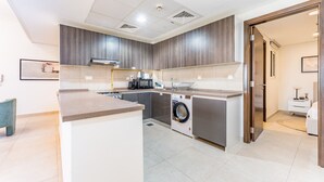 A modern kitchen with a built-in washing machine, a coffee machine, and a sink.