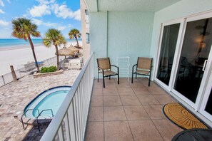 A balcony with a pool, chairs, and a view of the beach.