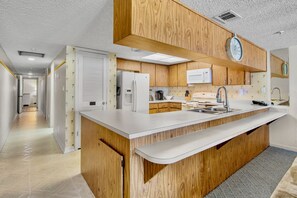 A modern kitchen with wooden cabinets, a white countertop, and a built-in microwave.