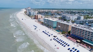 A coastal hotel with a beach view, multiple floors, and a pool area.