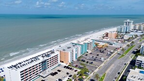 Un hotel frente al mar con varios pisos, aparcamiento y vistas a la playa y al océano.